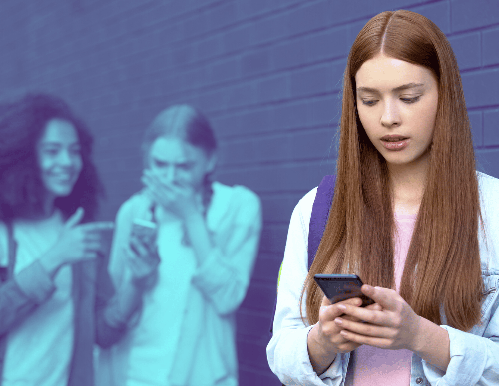 Teen looking at smartphone while other teens laugh in the background