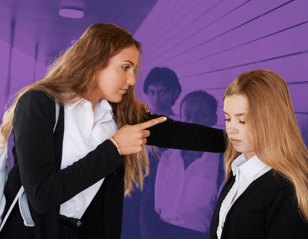 A teen girl bullying another girl while others watch