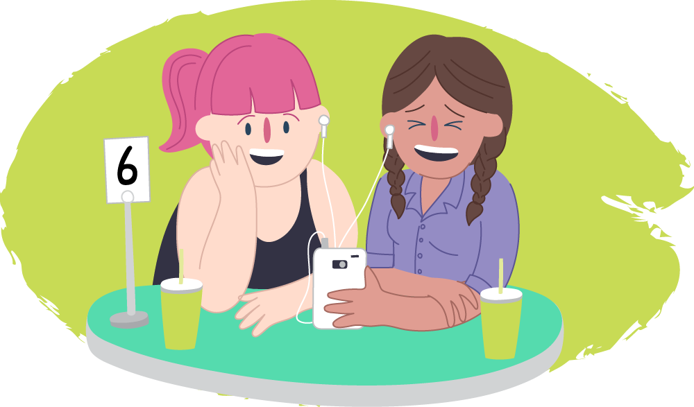 Two teen girls in a cafe laughing over their phones together