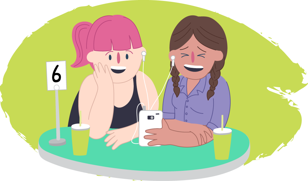 Two teen girls in a cafe laughing over their phones together